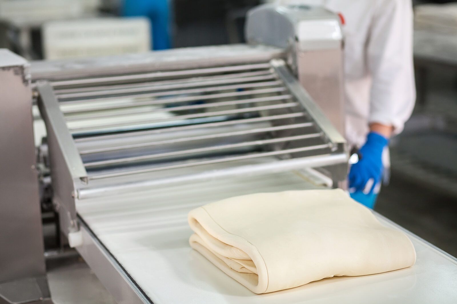 Bloque de masa de hojaldre plegado sobre la cinta de una laminadora industrial