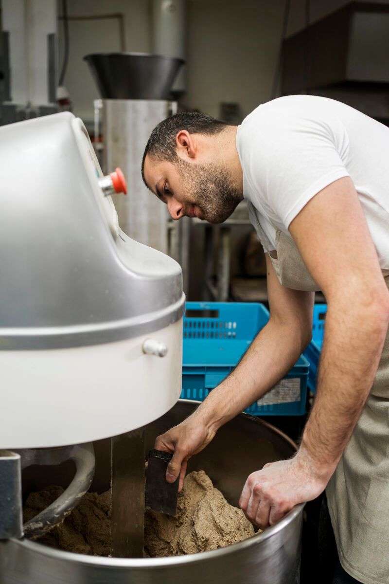 Operario trabajando con maquinaria de masa en una fábrica de pan