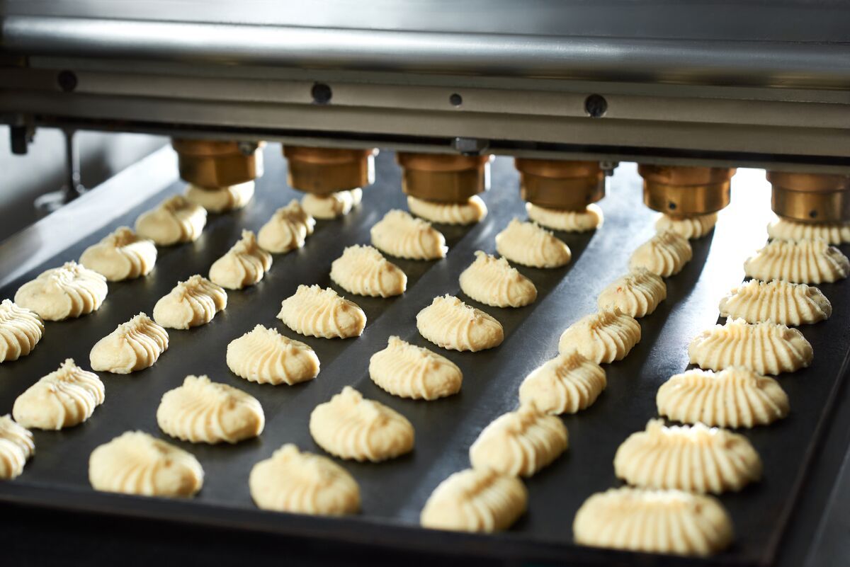 Piezas de masa cruda dosificadas en bandejas sobre una línea de producción